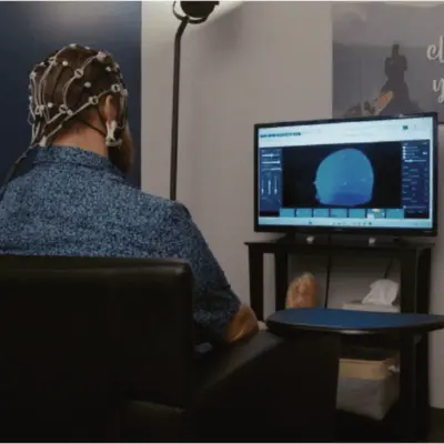 man receiving brain training wearing neurofeedback sensor cap man receiving brain training wearing neurofeedback sensor cap